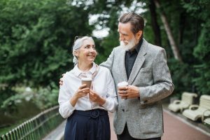 Caucasian elder couple standing at park with cups of coffee